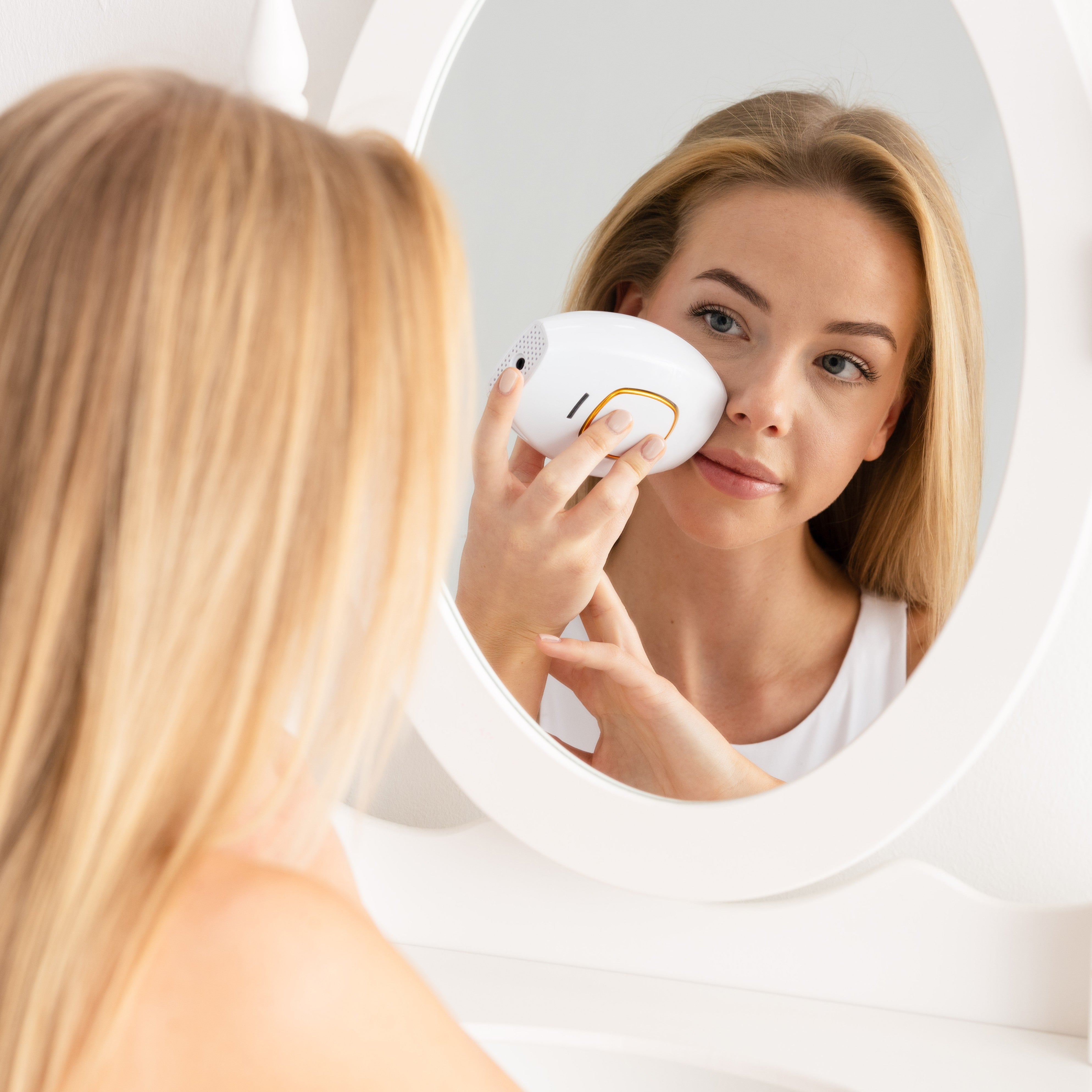 Hand holding a white skincare device with metallic spheres.